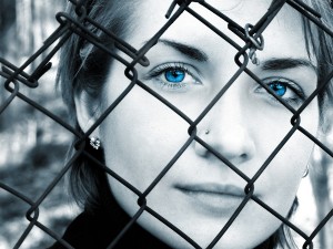 B&W picture of crying girl behind metal fence