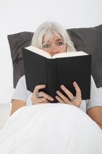 Close up of a Mid age woman reading book in bed, from high angle