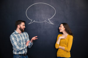 Happy young couple talking over chalkboard background with drawn